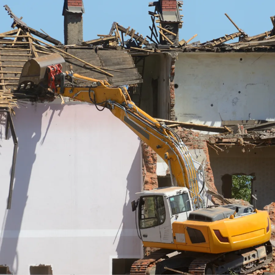 demolition-1 Yellow excavator demolishing the upper floor of an old building with a claw attachment.